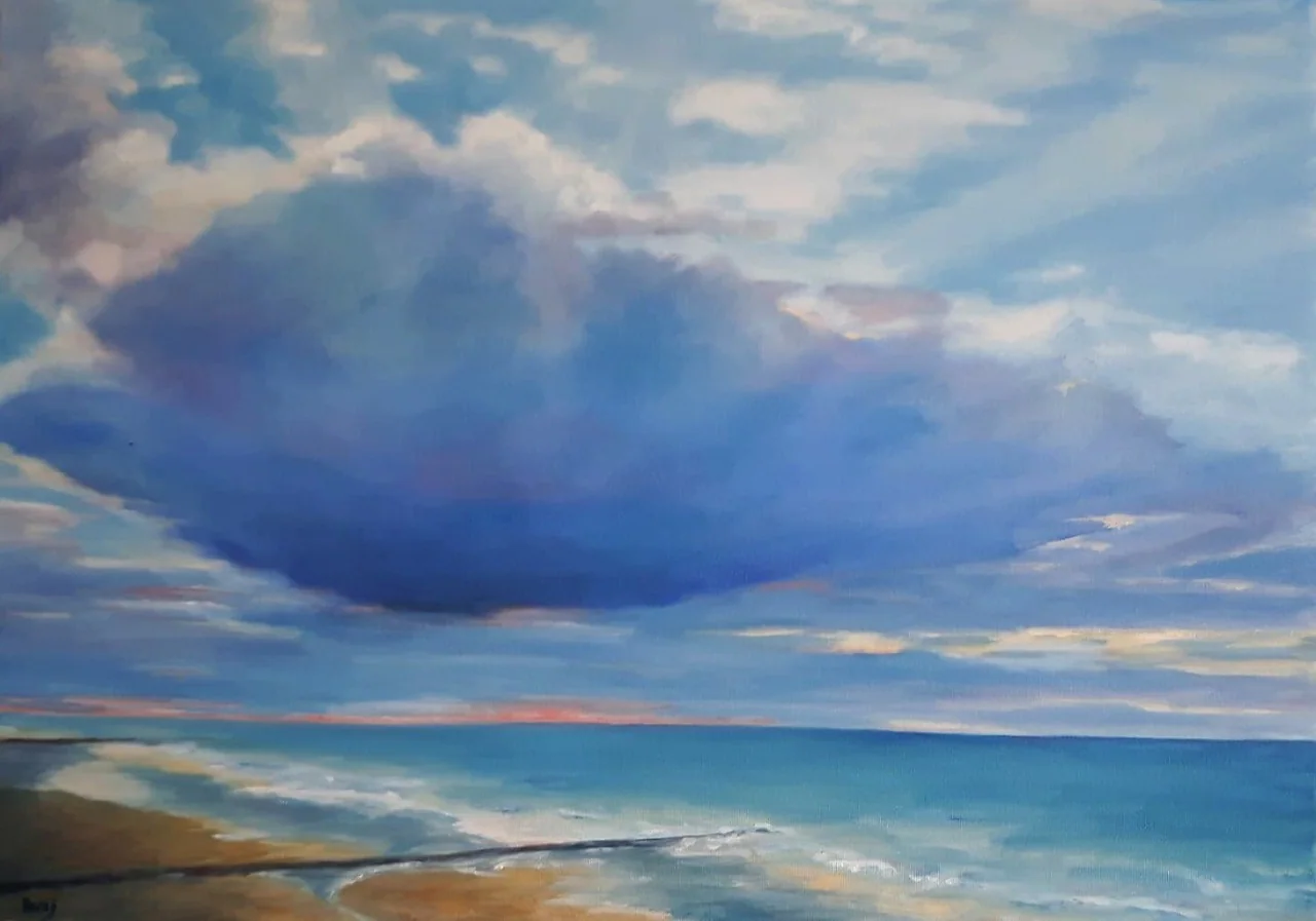 Un grand nuage bleu sombre au-dessus de la mer et de la plage.