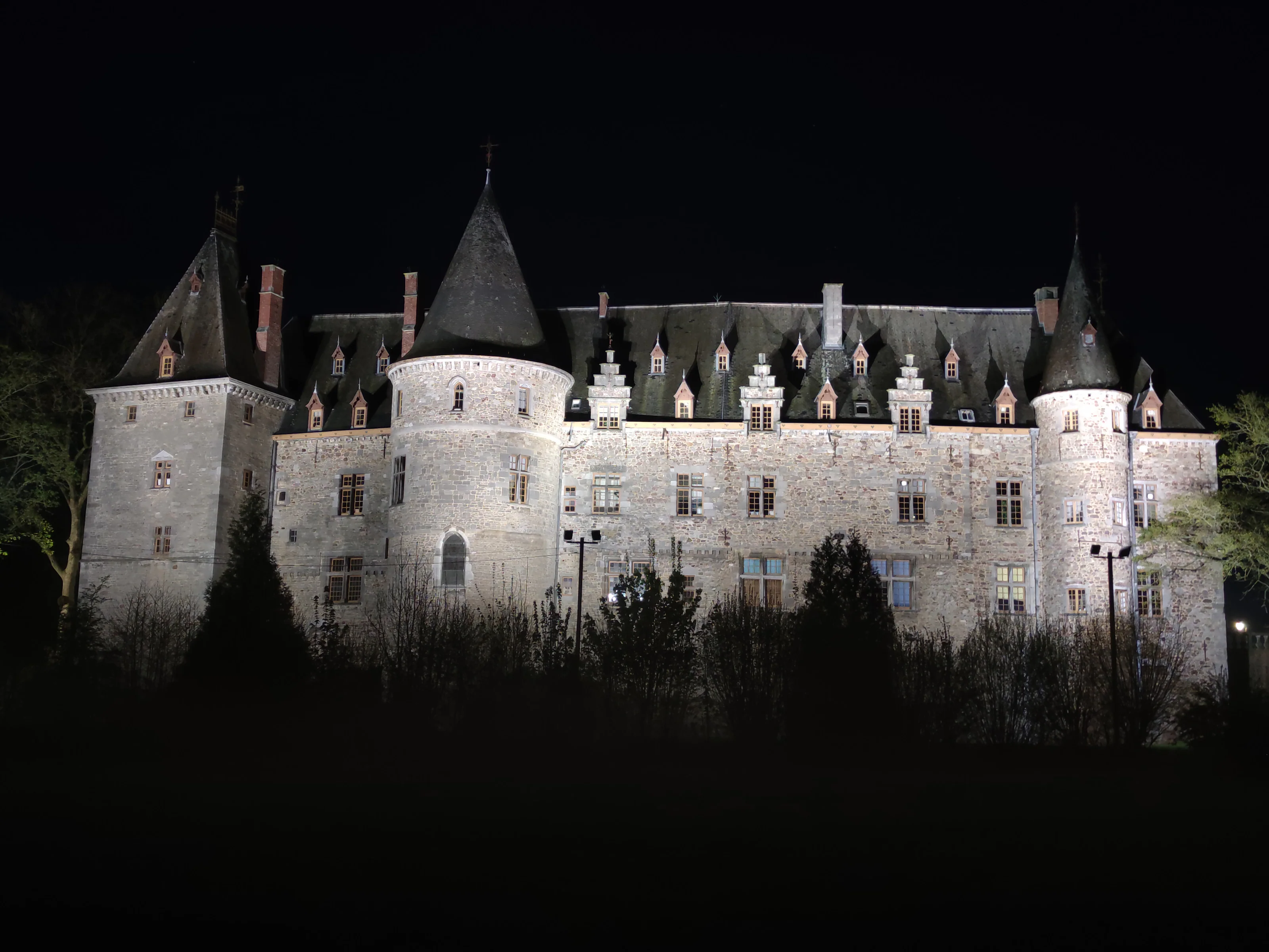 La longue façade du château illuminée, ses tours, ses lucarnes et ses pignons à gradins.