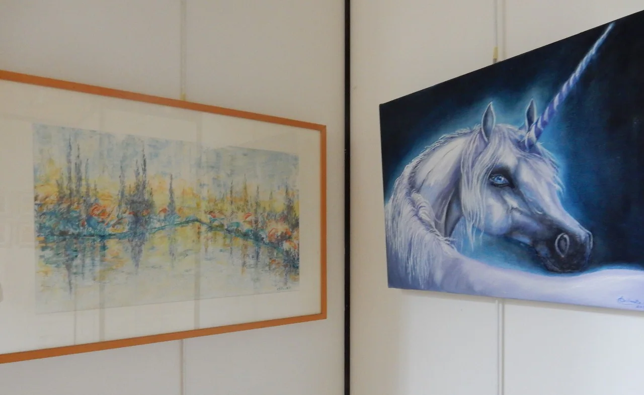Deux tableaux accrochés côte à côte, un paysage d'eau et une licorne.