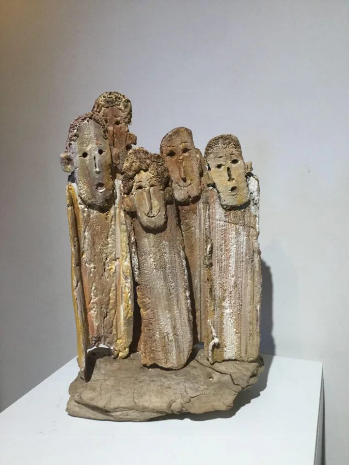Un groupe de personnages serrés, modelés en terre.