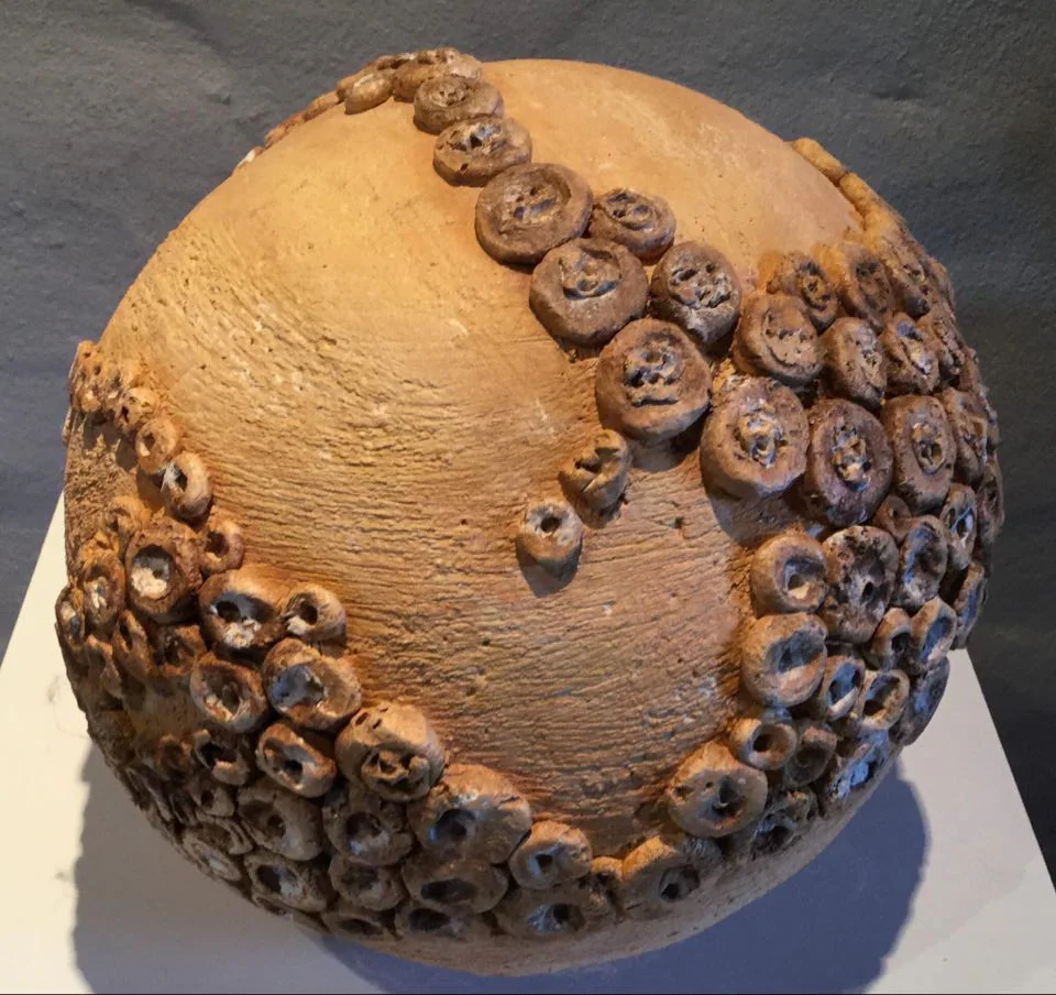 Une sphère en céramique ocre parcourue de petites spirales.