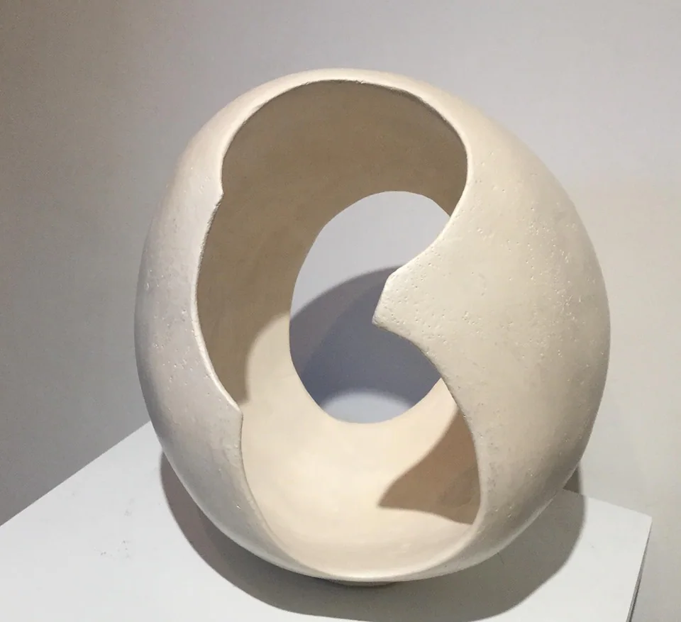 Une sculpture blanche en forme d'anneau enroulé sur lui-même.