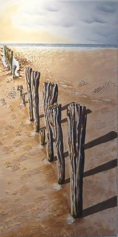 Une rangée de vieux piquets de bois sur une plage, jusqu'à la mer.